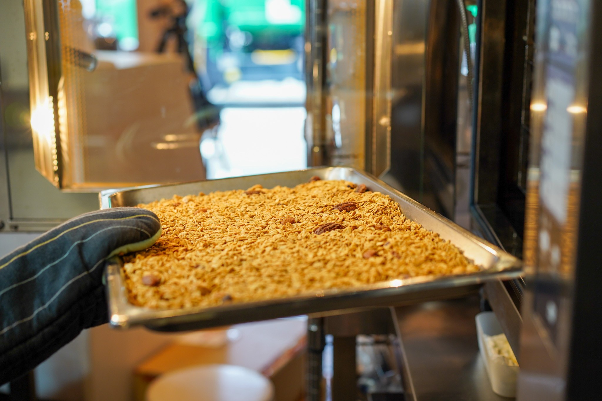 焼き上がったグラノーラの天板を、オーブンから取り出す手元
